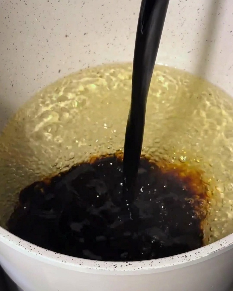 Salsa oscura siendo vertida en una olla que contiene una base más clara.