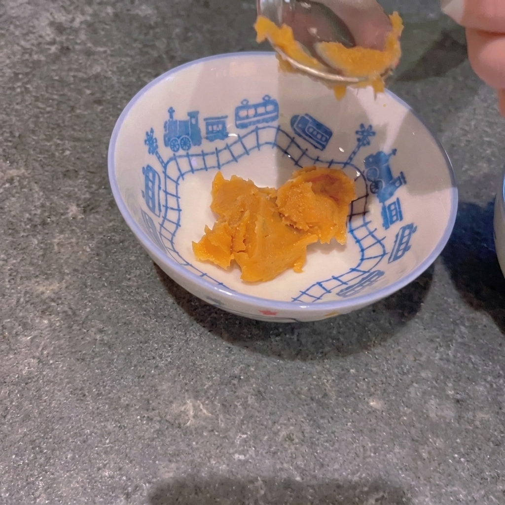 Una cucharada de pasta de miso amarilla colocada en un tazón pequeño con un patrón de trenes.