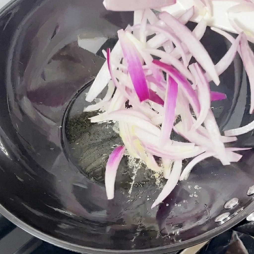Tiras de cebolla morada salteándose en un wok.