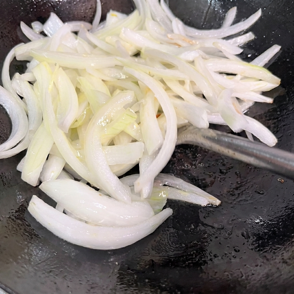 Cebollas en rodajas salteándose en un wok caliente.