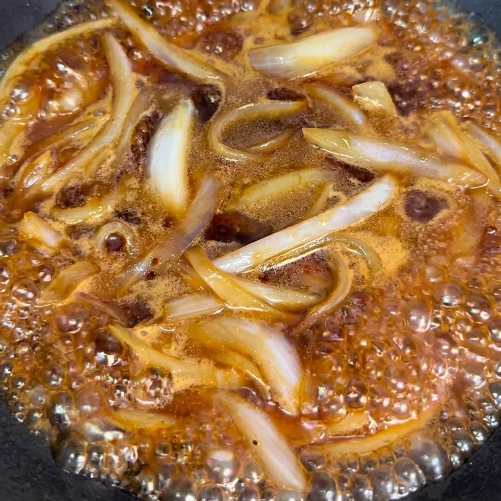 Rollitos de ternera escaldados añadidos al wok con cebollas y salsa.