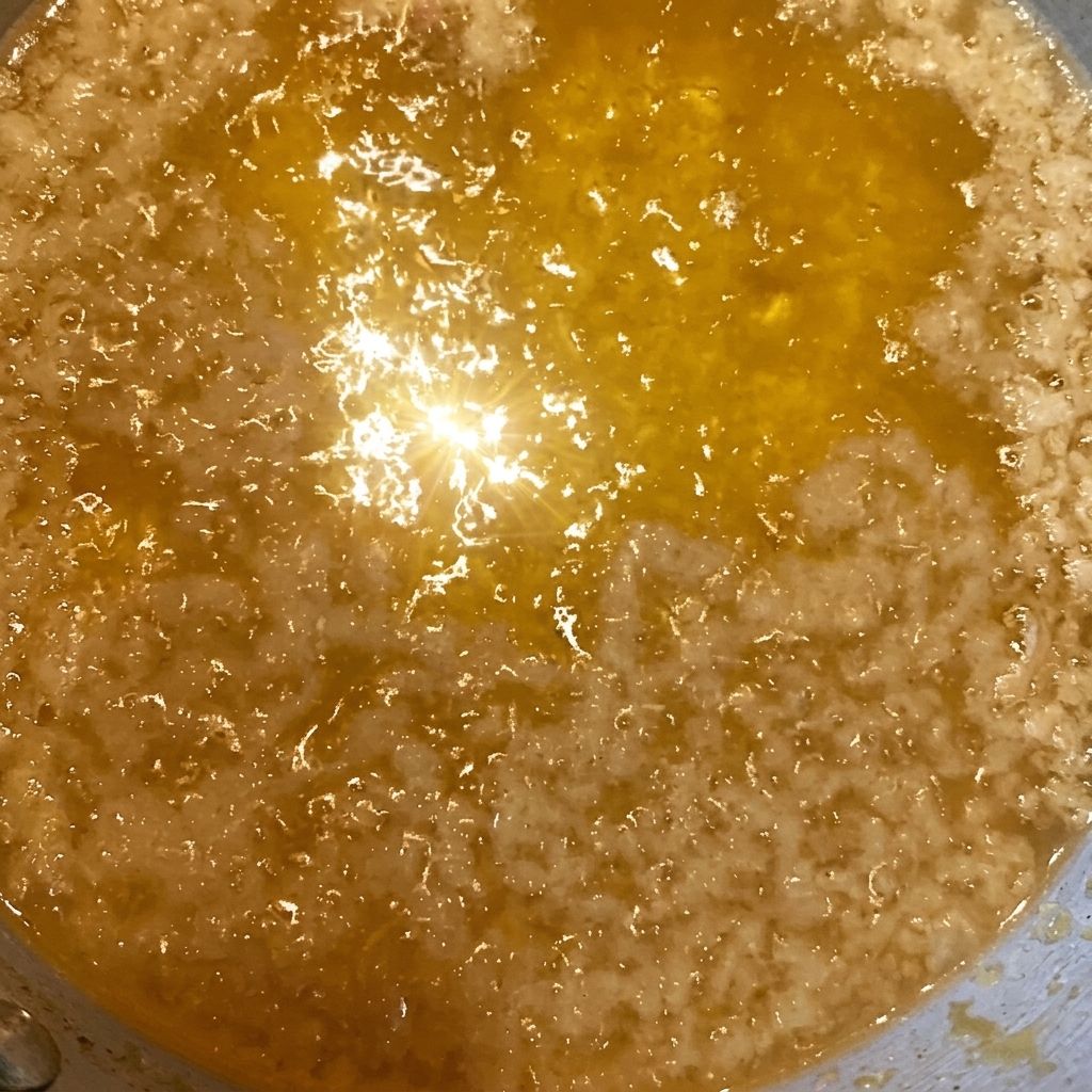 Primer plano de migas de tempura doradas esparcidas sobre un tazón de arroz con salsa.