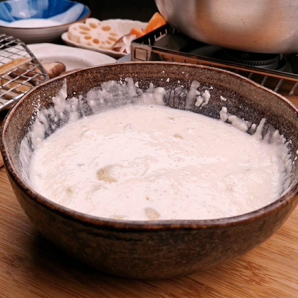 Agua helada siendo vertida en un bol con harina de tempura para crear una mezcla suave.