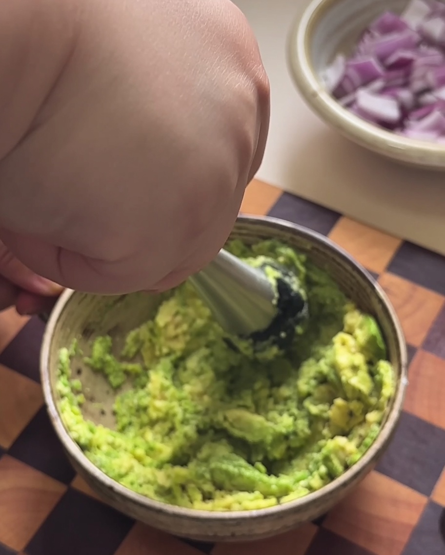 Pulpa de aguacate siendo machacada hasta formar un puré en un bol.