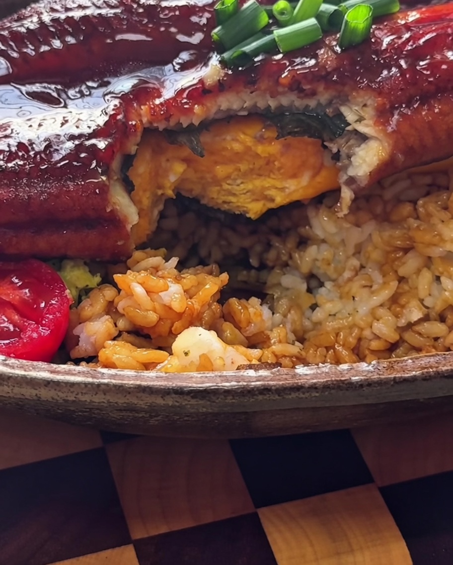 Una tortilla tamagoyaki amarilla colocada sobre la base de arroz.
