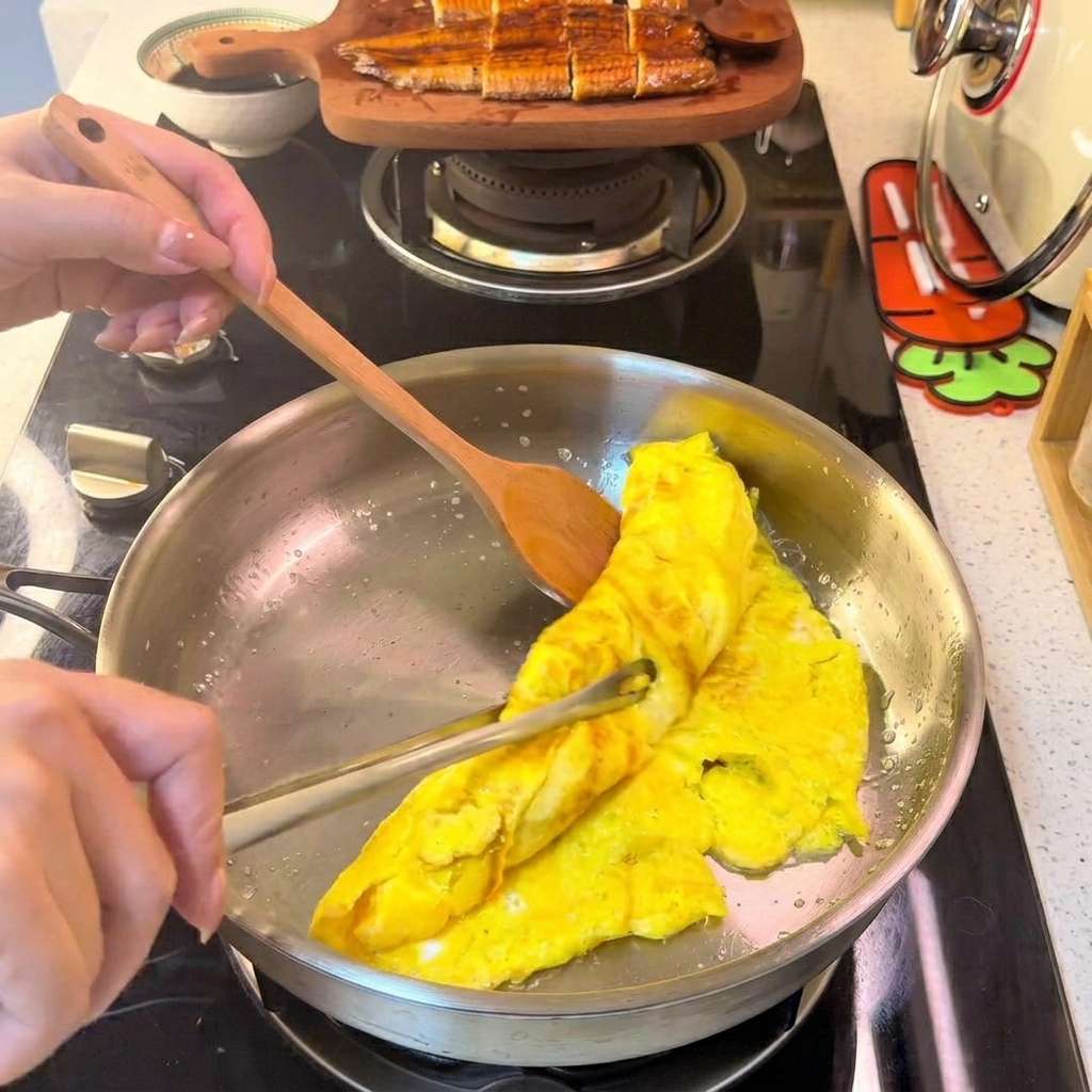 Una tortilla de huevo enrollada siendo cortada en tiras finas y uniformes sobre un plato blanco.