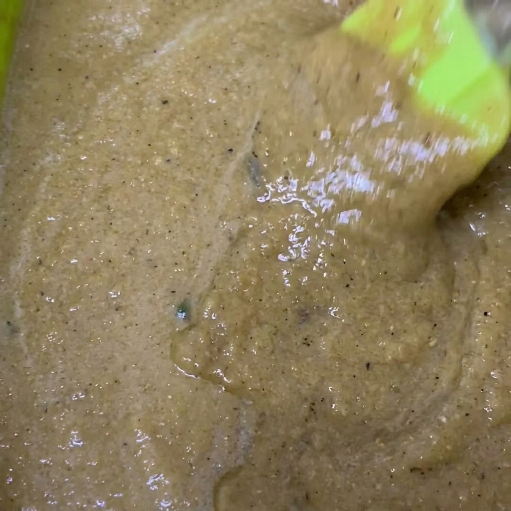 Un tazón verde con el puré de marinado al que se le añade salsa de soja y pimienta negra.