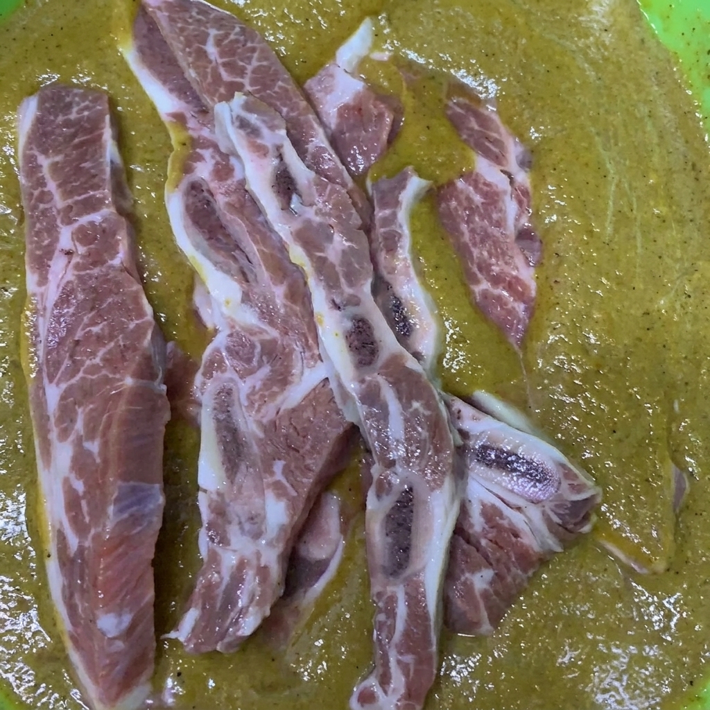 Costillas de res siendo mezcladas y cubiertas en un tazón lleno del marinado estilo coreano preparado.