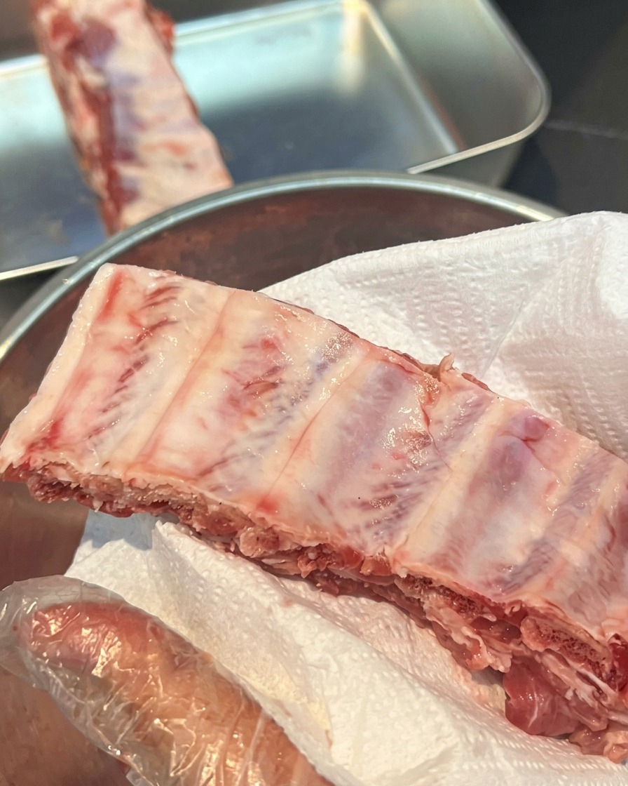 Costillas de cerdo crudas sobre papel absorbente para eliminar la humedad.