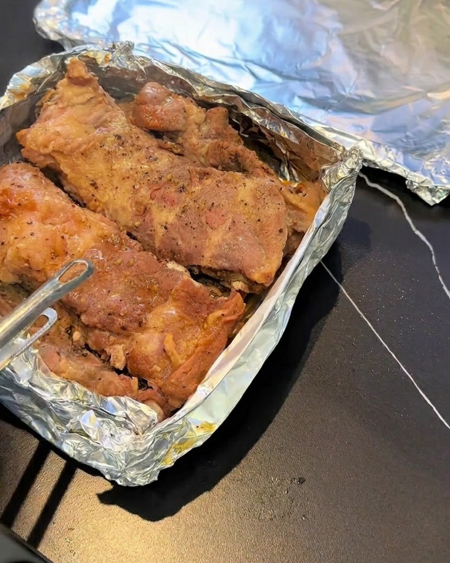 Costillas al vapor sobre una bandeja de horno forrada con papel aluminio.