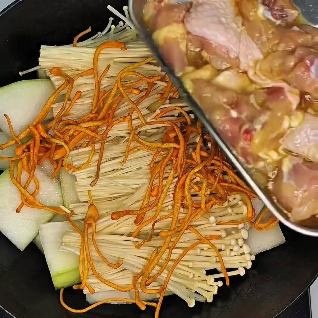 Una mano enguantada mezclando y masajeando los muslos de pollo en un tazón con marinado.