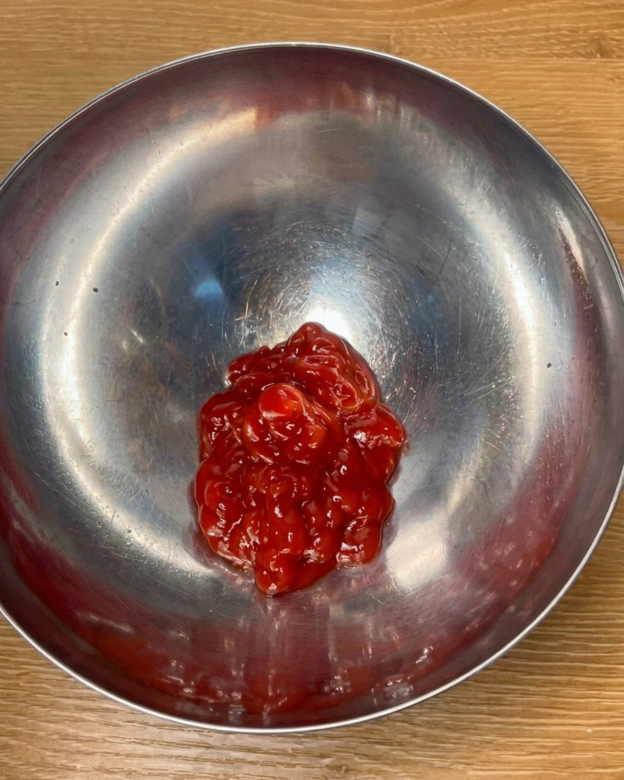 Ketchup de tomate y condimentos mezclándose en un tazón de metal para crear una salsa sabrosa.