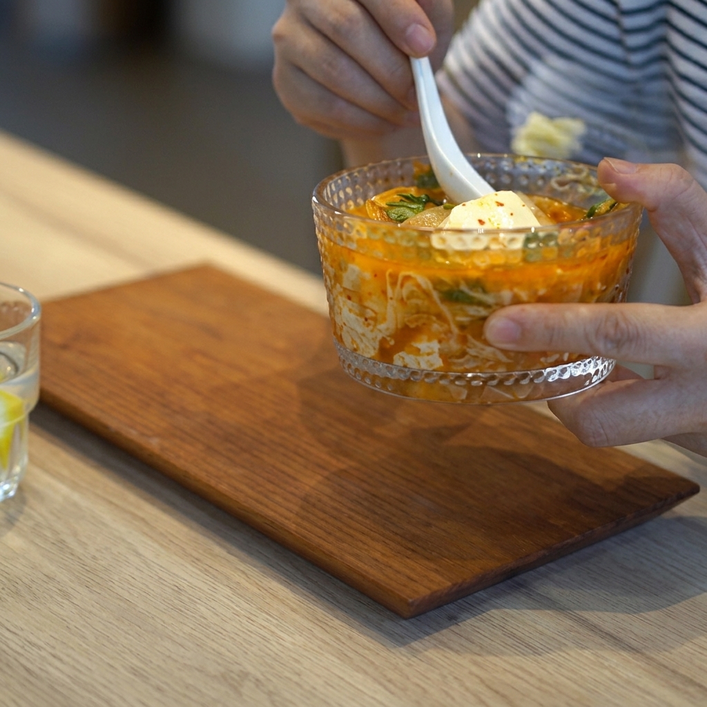 Champiñones enoki frescos siendo colocados en la olla con la base de sopa de kimchi.