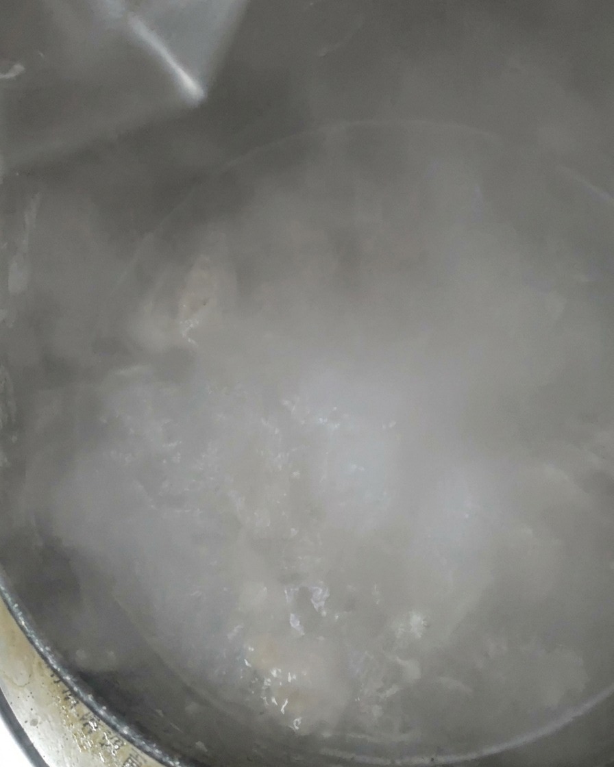 Agua clara siendo vertida en una olla que hierve a fuego lento.