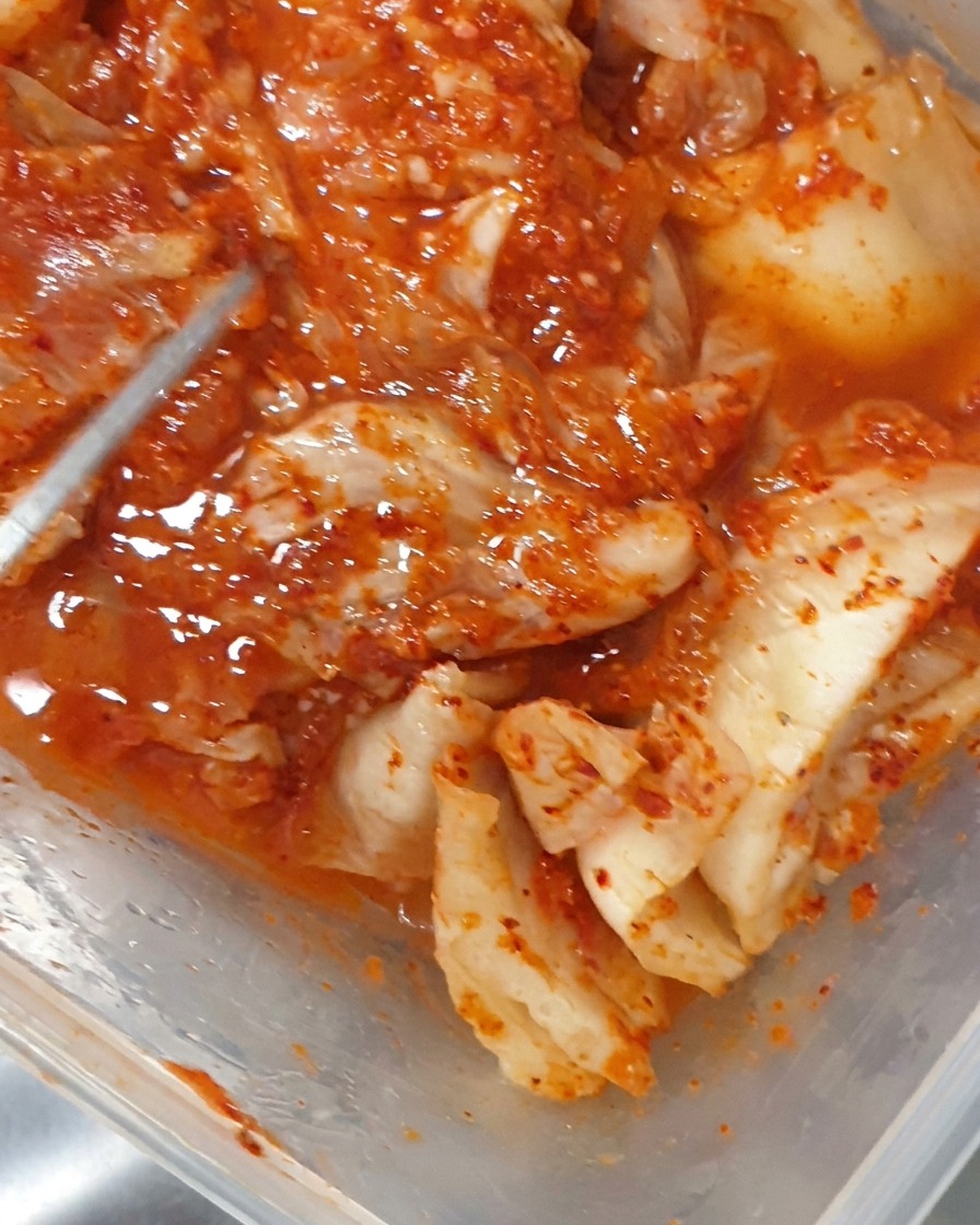 Pinzas colocando trozos de kimchi fermentado en una olla burbujeante.