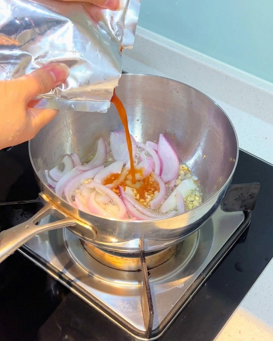 Kimchi vertido en la olla y mezclado con la cebolla y el ajo.