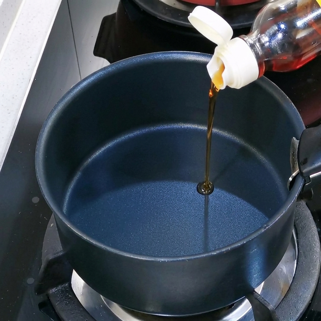 Aceite de sésamo vertido en una olla negra vacía sobre la estufa.