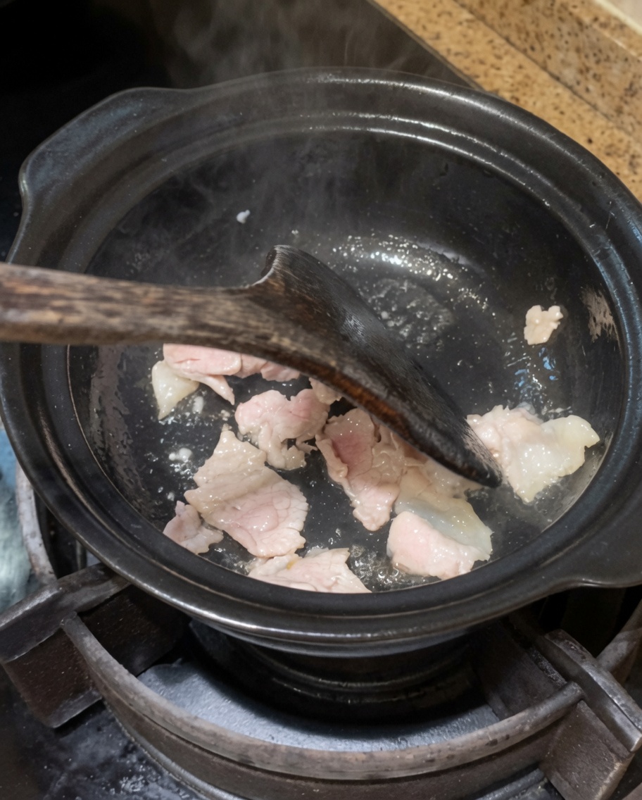 Cebolla y ajo siendo salteados en la olla con el cerdo.