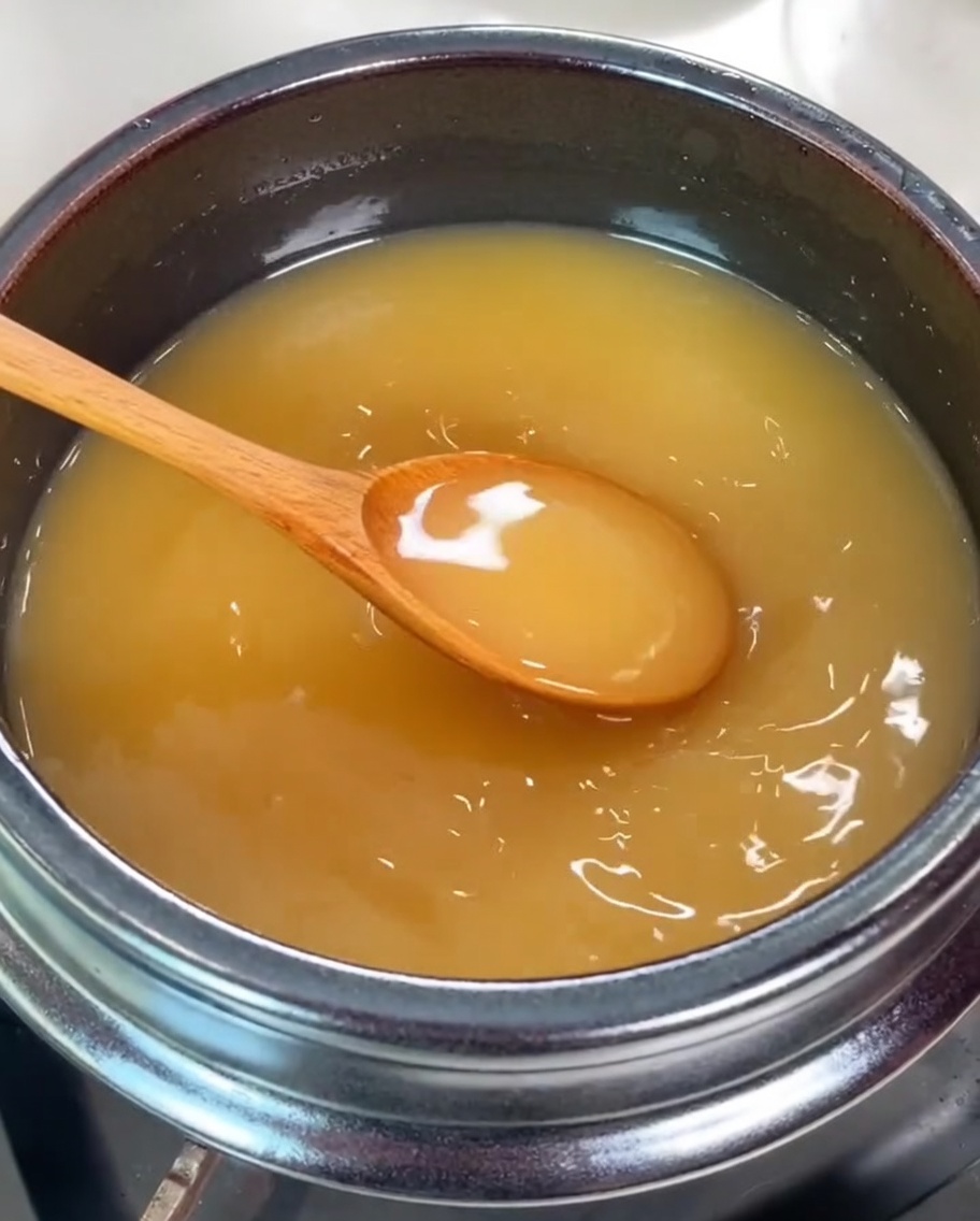 Varias almejas frescas siendo añadidas a la olla con el caldo de soja.