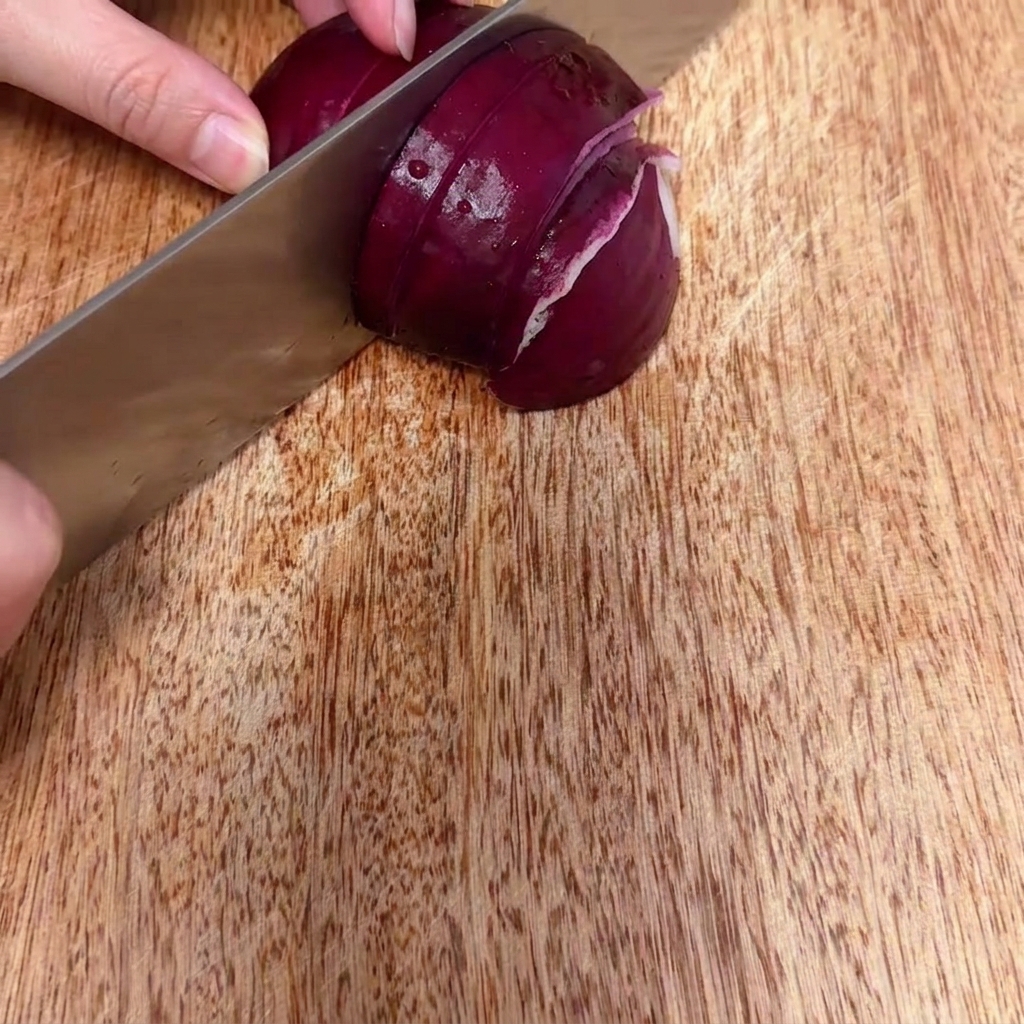 Cebolla roja cortándose en trozos finos y pequeños sobre una superficie de madera.