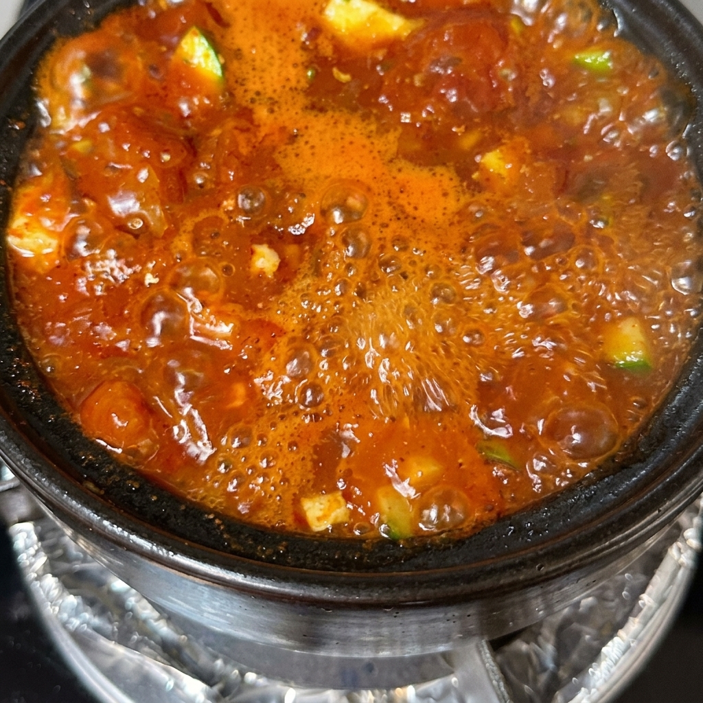 Una olla terminada de sopa de tofu decorada con cebolletas en rodajas y rodajas de chile.