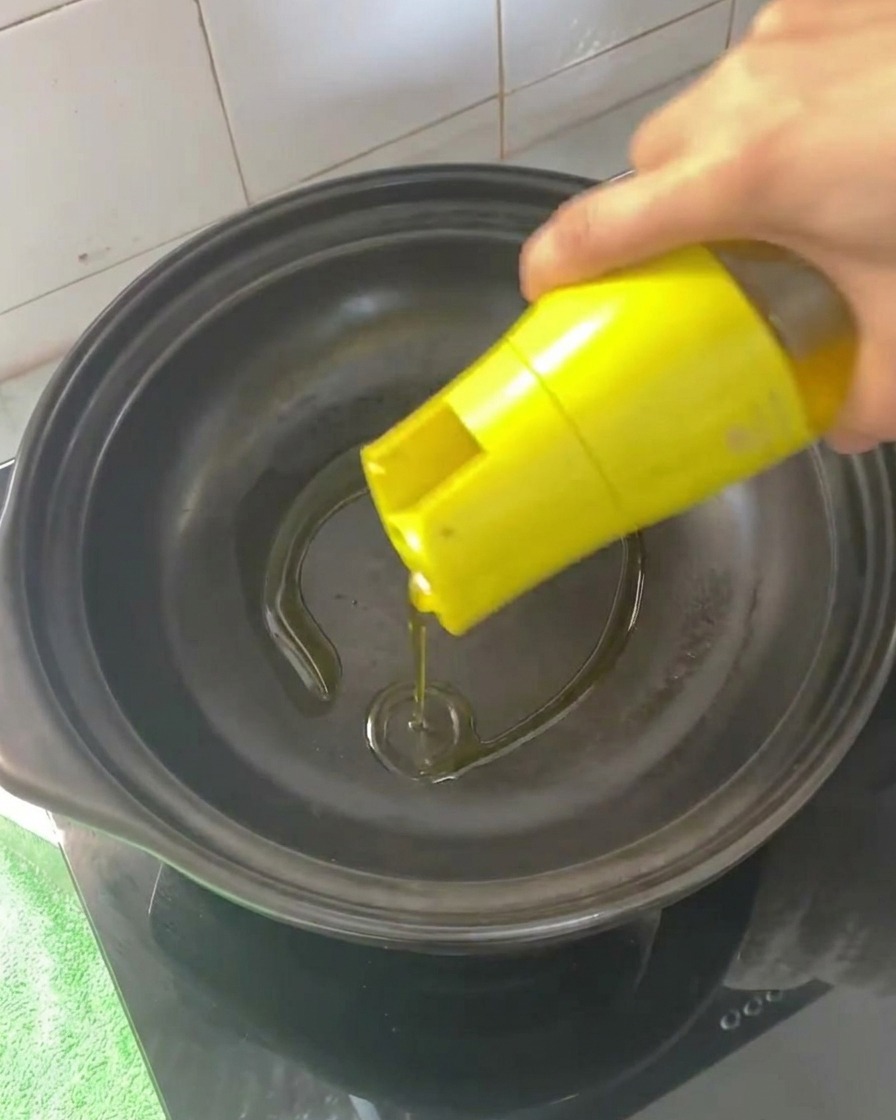 Aceite de cocina vertido en una cazuela de barro vacía y caliente.