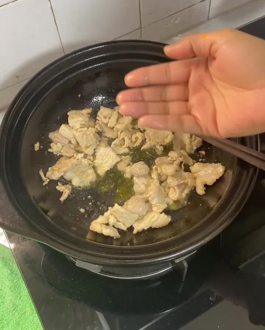 Jengibre, ajo, cebollinos y chile seco siendo incorporados a la panceta cocinada.