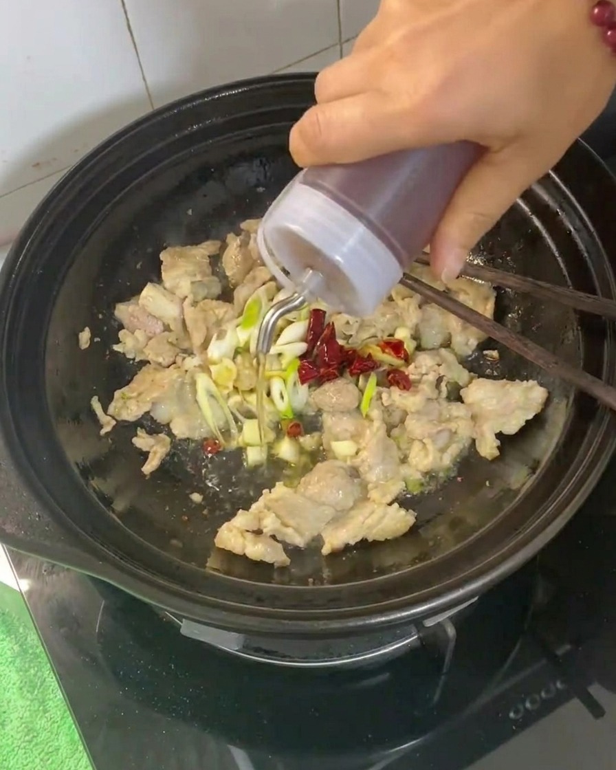Vino de cocina siendo vertido en la cazuela con la carne y los aromáticos.