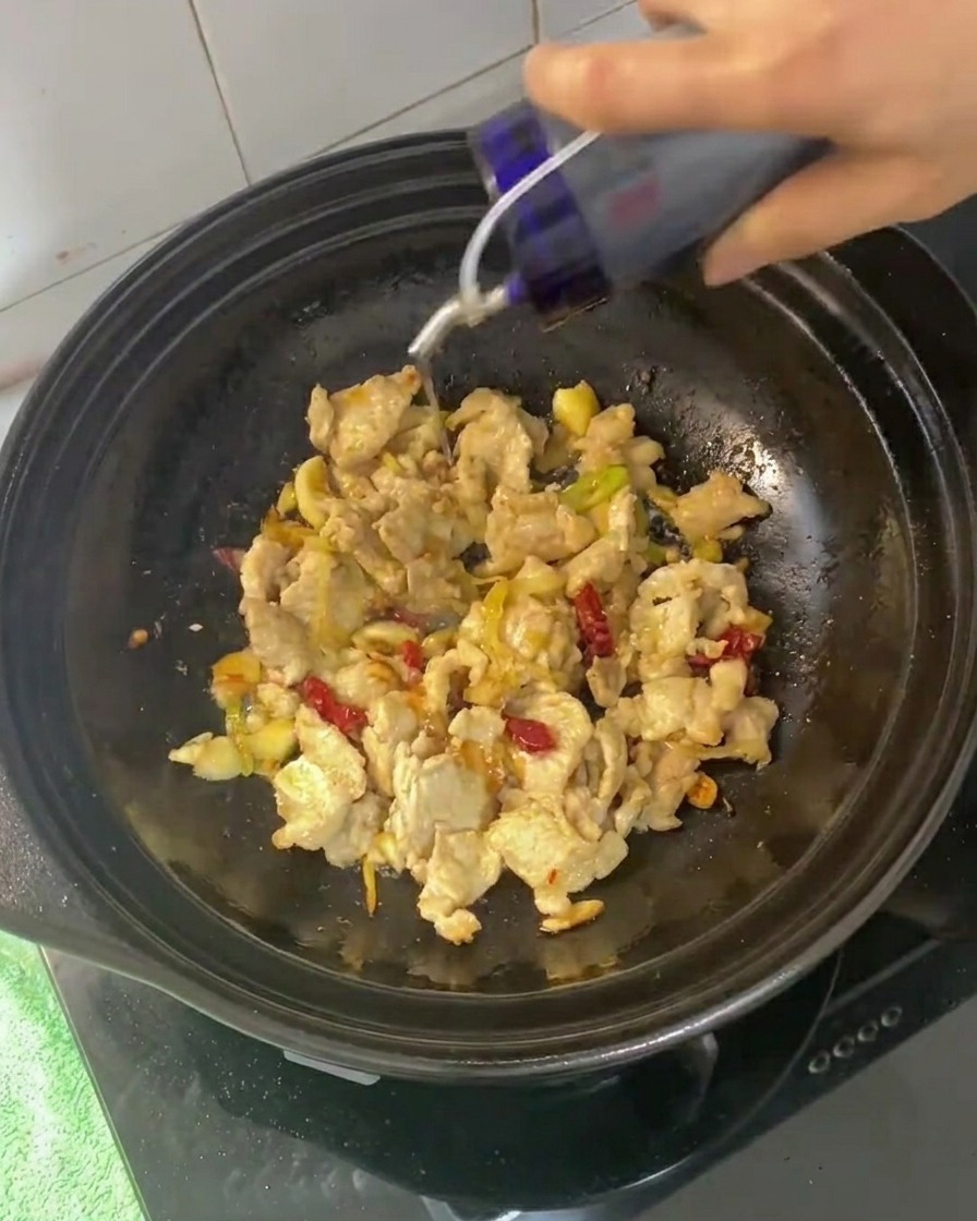 Salsas de soja y salsa de ostras siendo añadidas a la mezcla de panceta salteada.