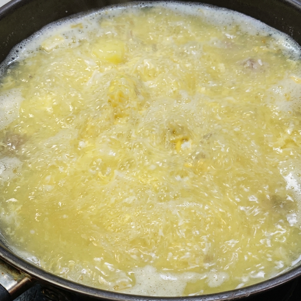 Sal y pimienta blanca siendo añadidas a la sopa de tofu y huevo salado.