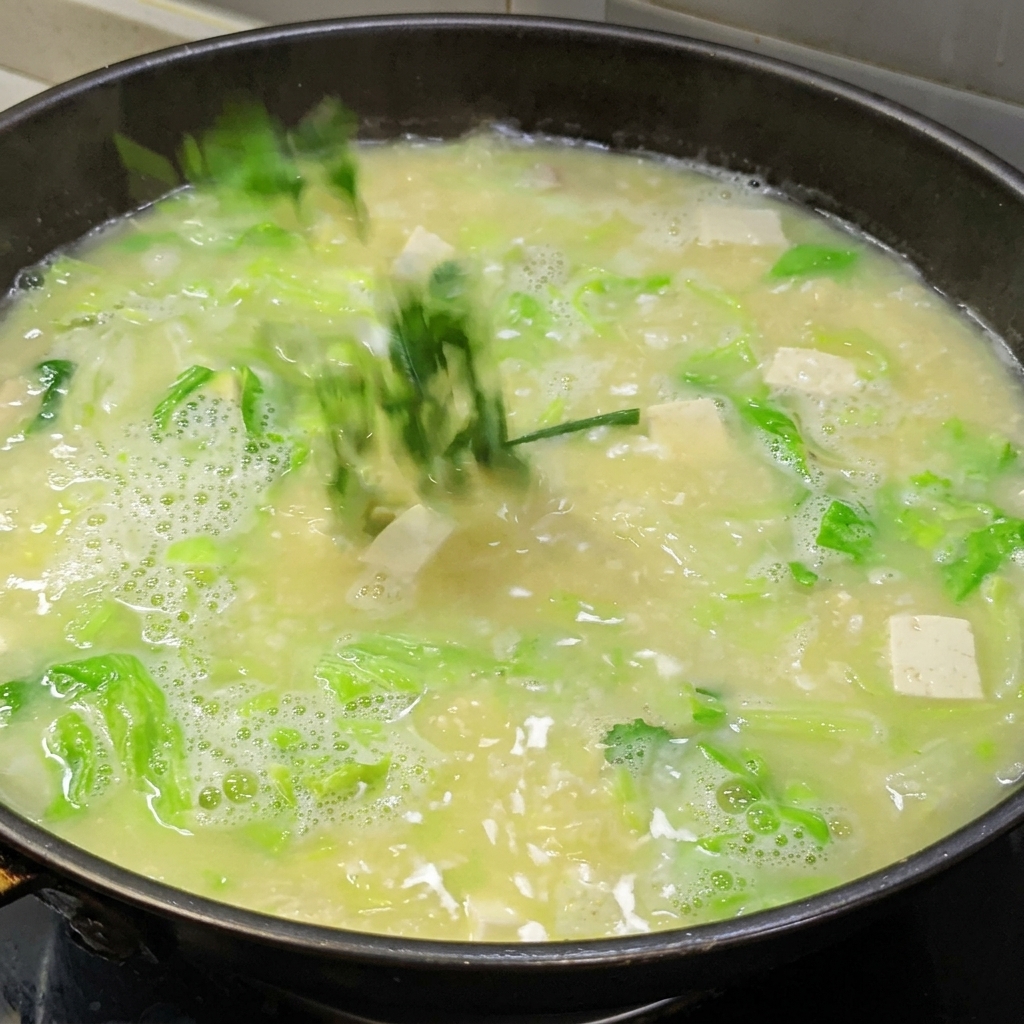 Mezcla de almidón y agua siendo vertida en una sopa de huevo salado y tofu para espesar el caldo.