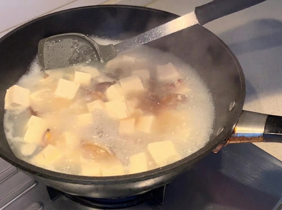 Salsa de soja siendo vertida en la sopa a fuego lento.