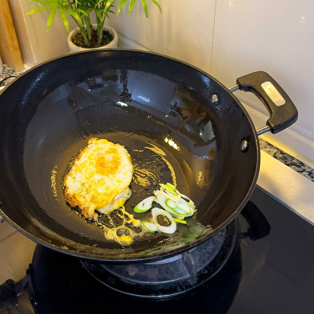Huevo frito y cebollinos picados chisporroteando en el wok.