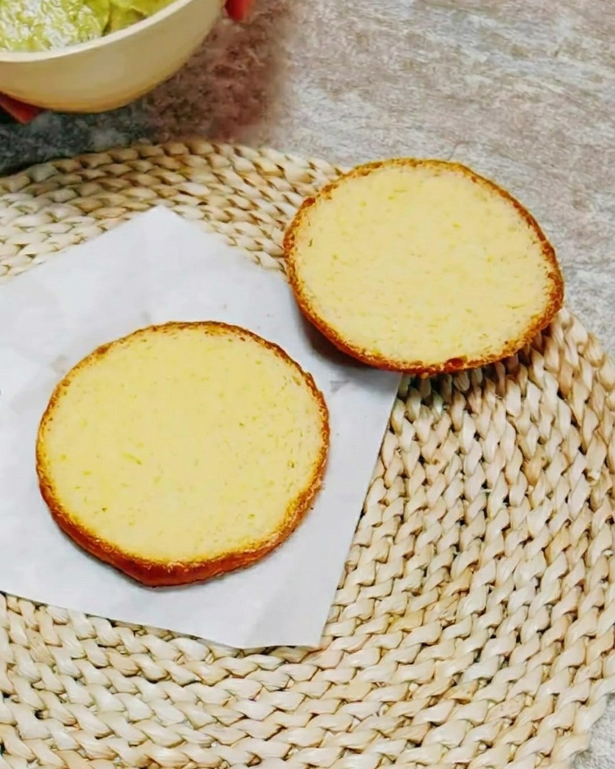 Los lados cortados de un pan de hamburguesa untados con una salsa cremosa de hierbas verdes.
