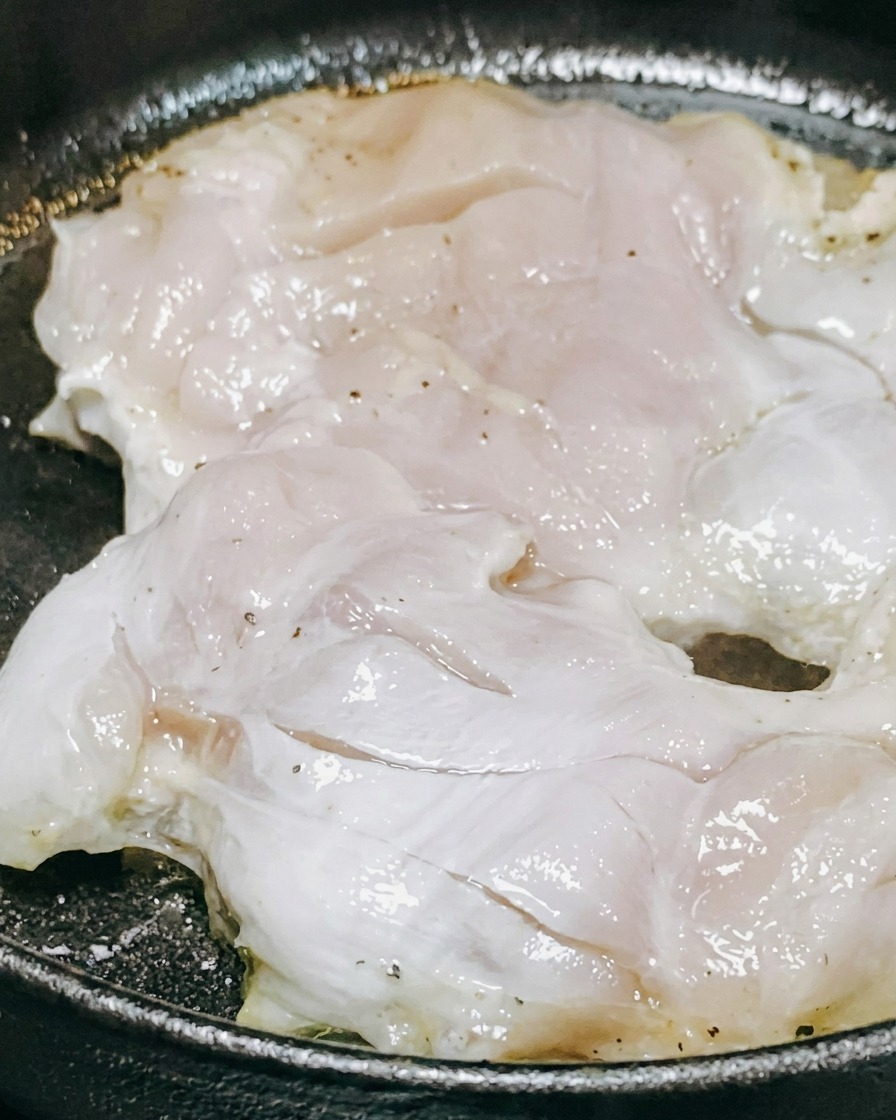 Salsa teriyaki y vino blanco siendo vertidos sobre piezas de pollo cocinándose en una sartén.