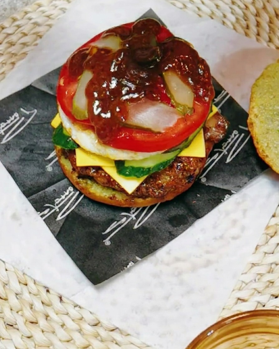 Primer plano de la hamburguesa siendo rociada con una salsa oscura y sabrosa de teriyaki mezclada con jugo de limón.