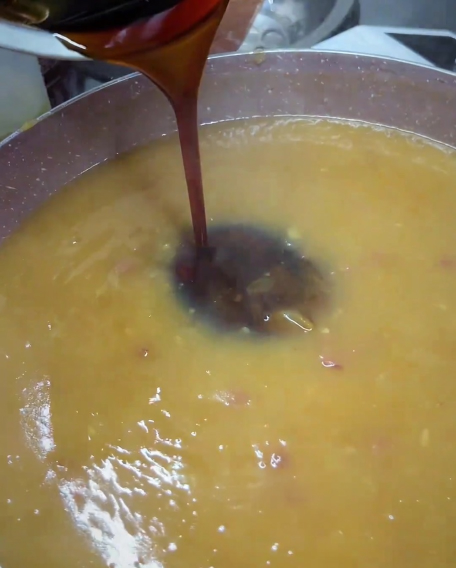 Salsa teriyaki oscura vertiéndose desde un pequeño cuenco a una sartén con salsa dorada licuada.