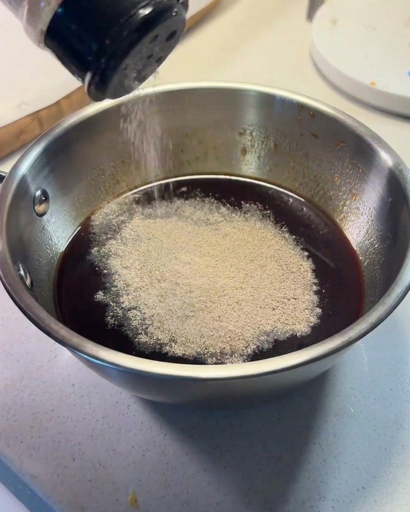 Ingredientes de la salsa combinándose en un pequeño cuenco metálico con pimienta negra espolvoreada encima.