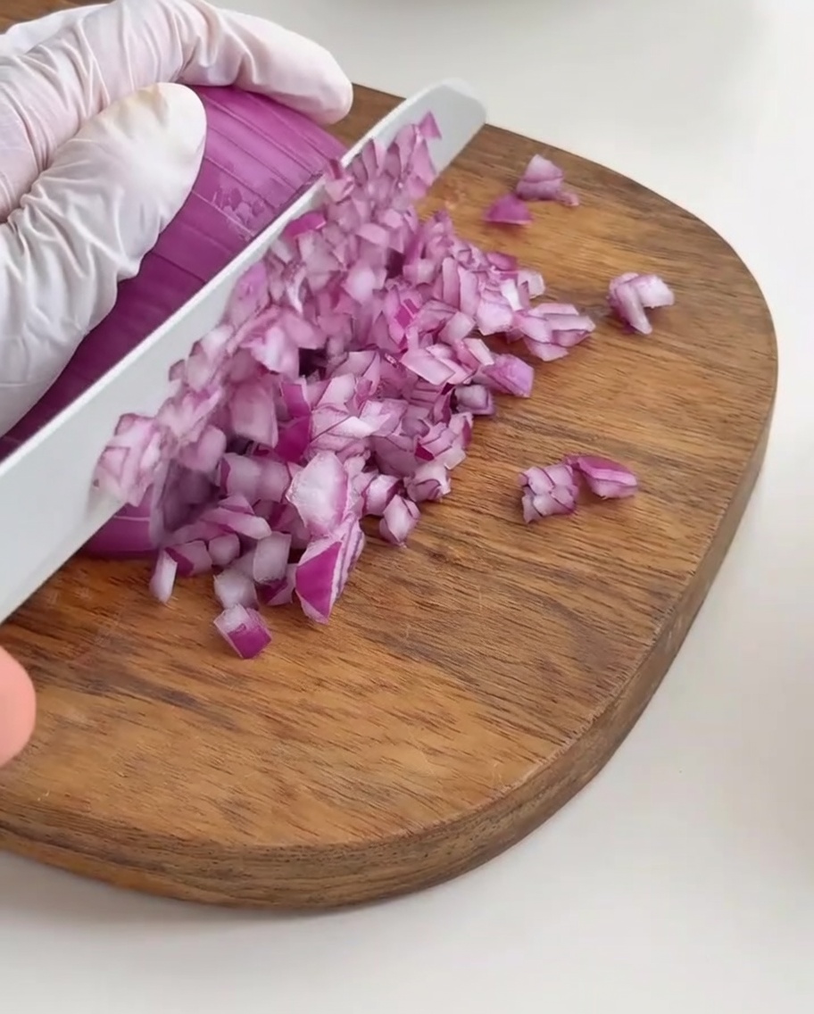 Cebolla morada finamente picada dispuesta sobre una tabla.