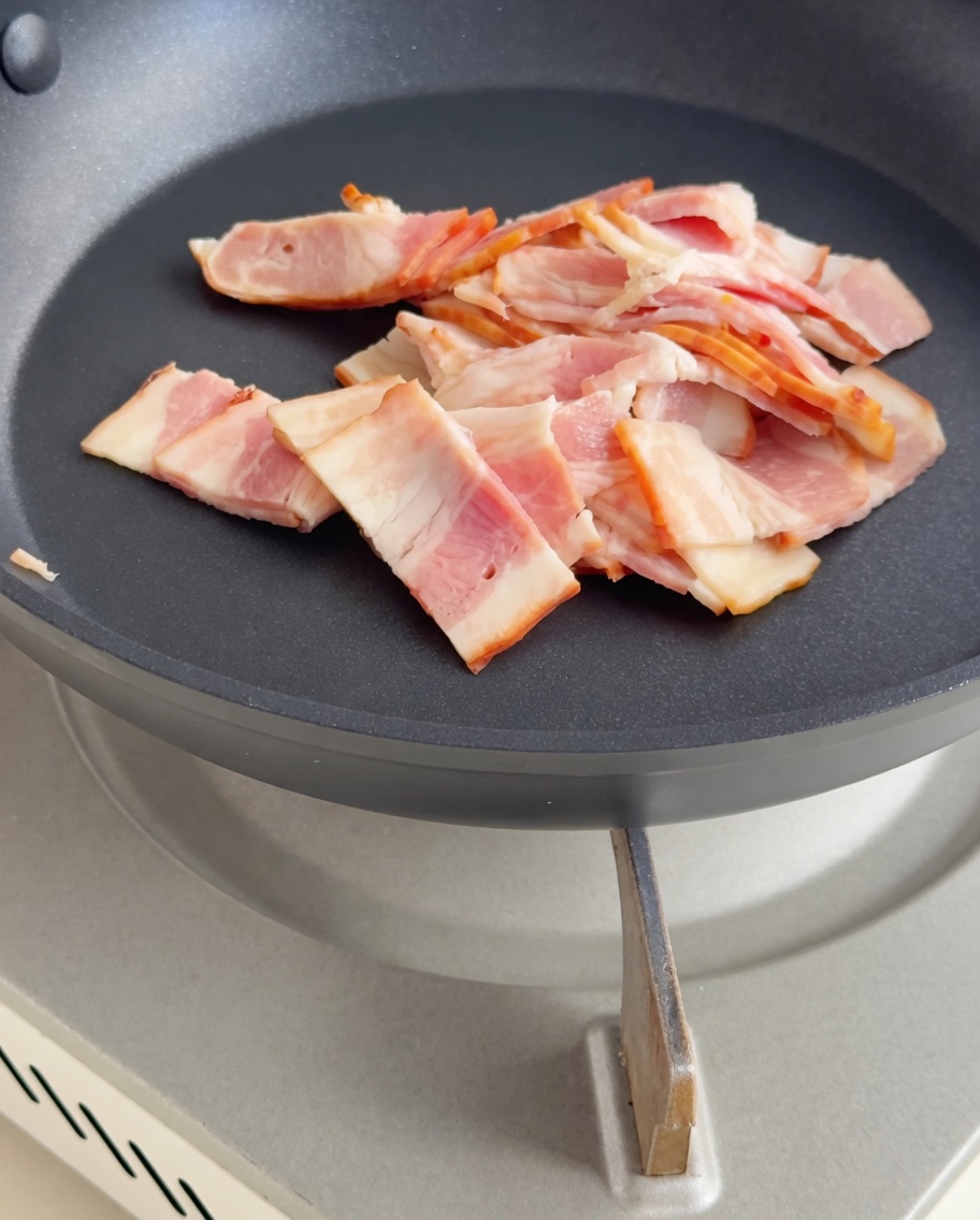 Trozos de tocino friéndose hasta estar crujientes.