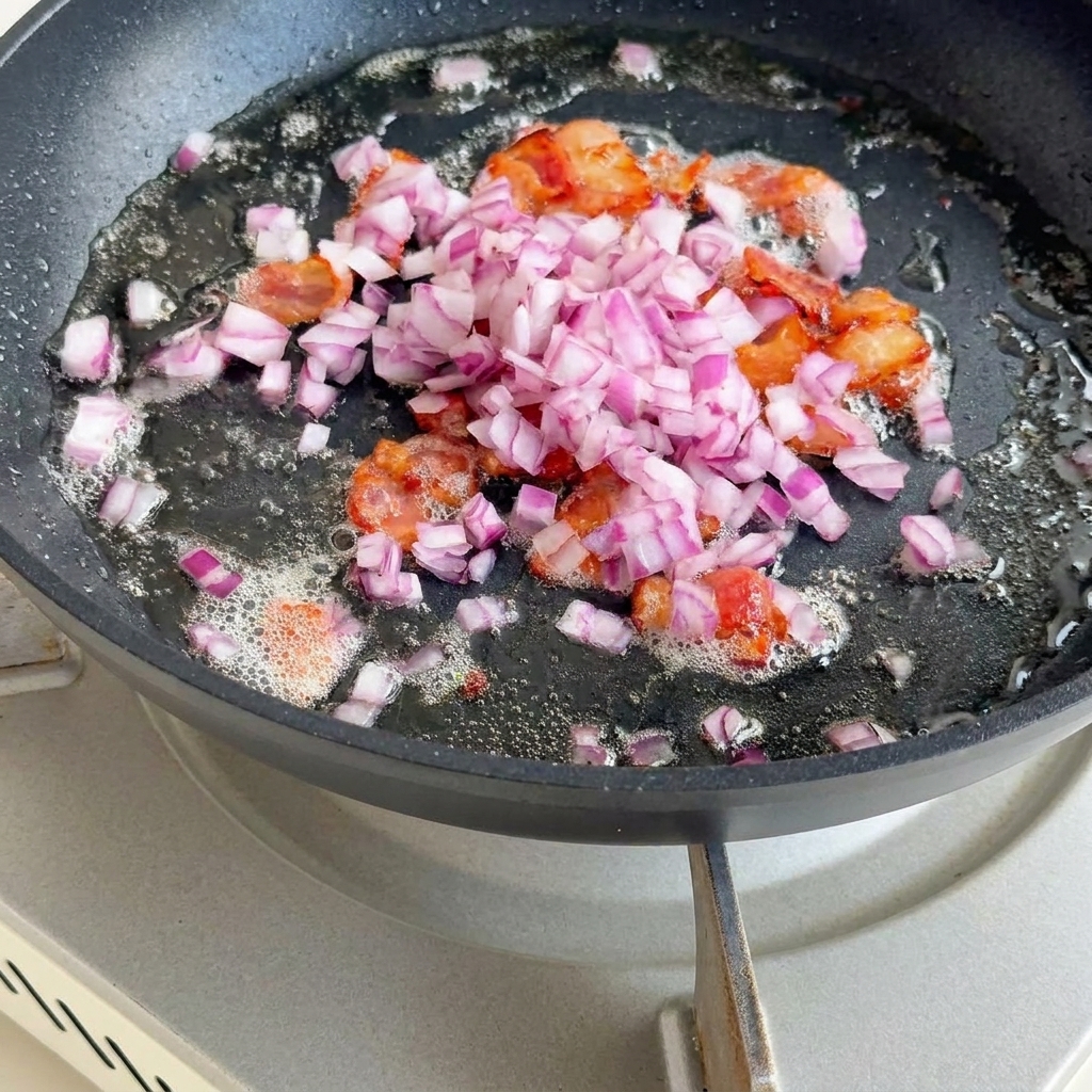 Cebolla, apio y patatas salteándose con los trozos de tocino.