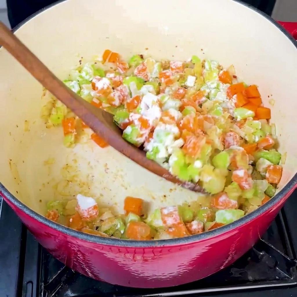 Harina siendo espolvoreada sobre los vegetales y mezclada constantemente.