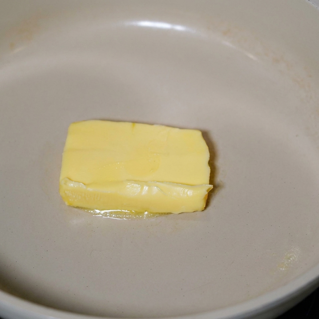 Tocino friéndose en mantequilla derretida en una sartén.