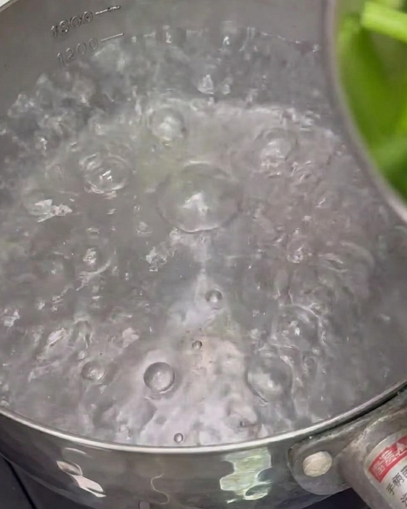 Trozos de espárragos hirviendo en una olla con agua para escaldarlos.