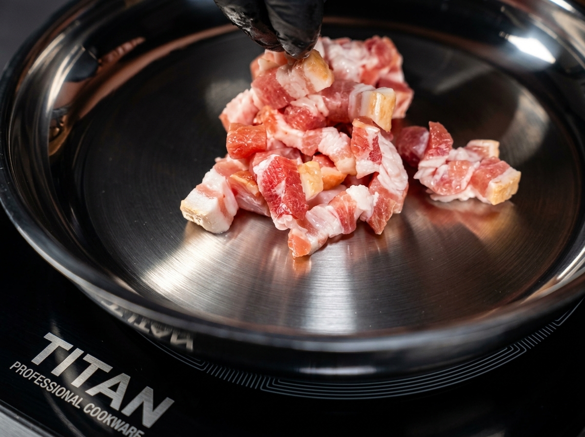 Trozos de tocino dorándose en una sartén metálica caliente, removidos con pinzas de puntas negras.