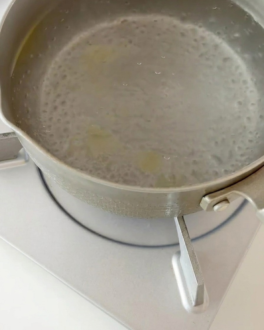 Fusilli cocido siendo escurrido de agua hirviendo en un colador de cocina.