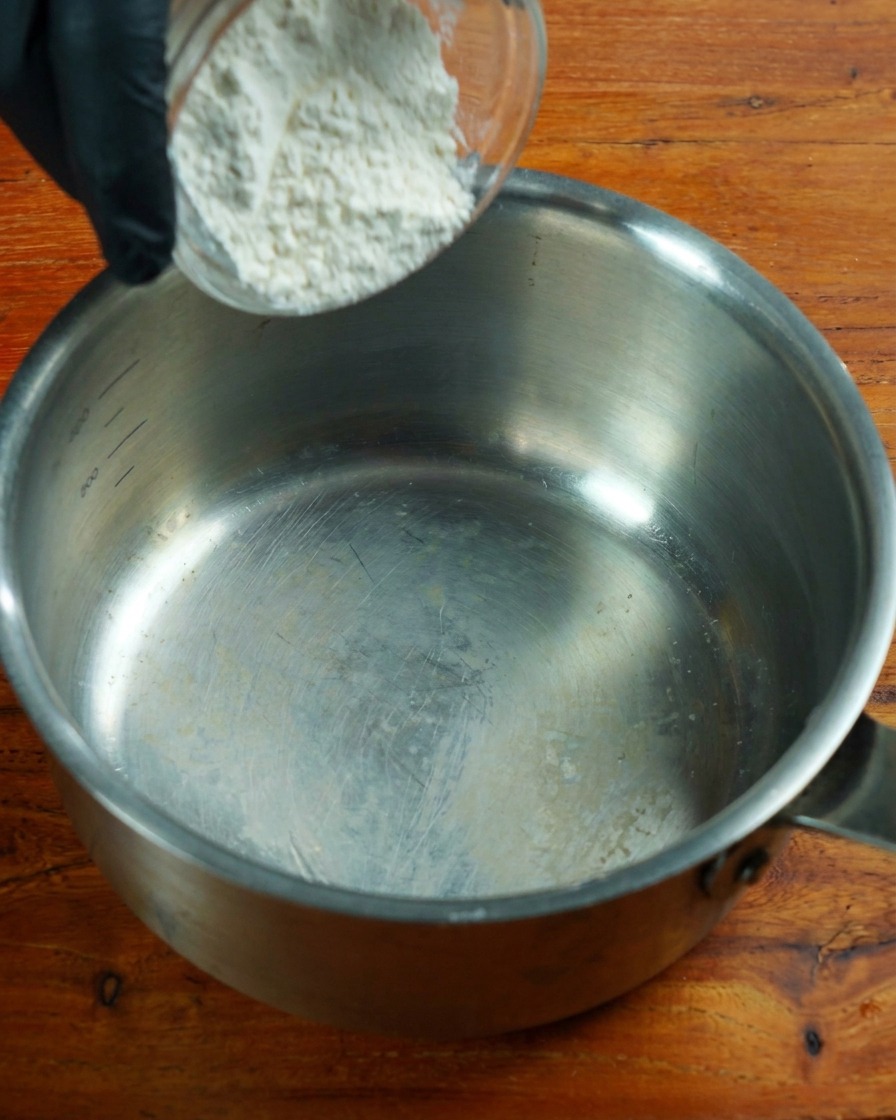Harina baja en proteínas siendo removida en una olla de acero inoxidable a fuego lento.
