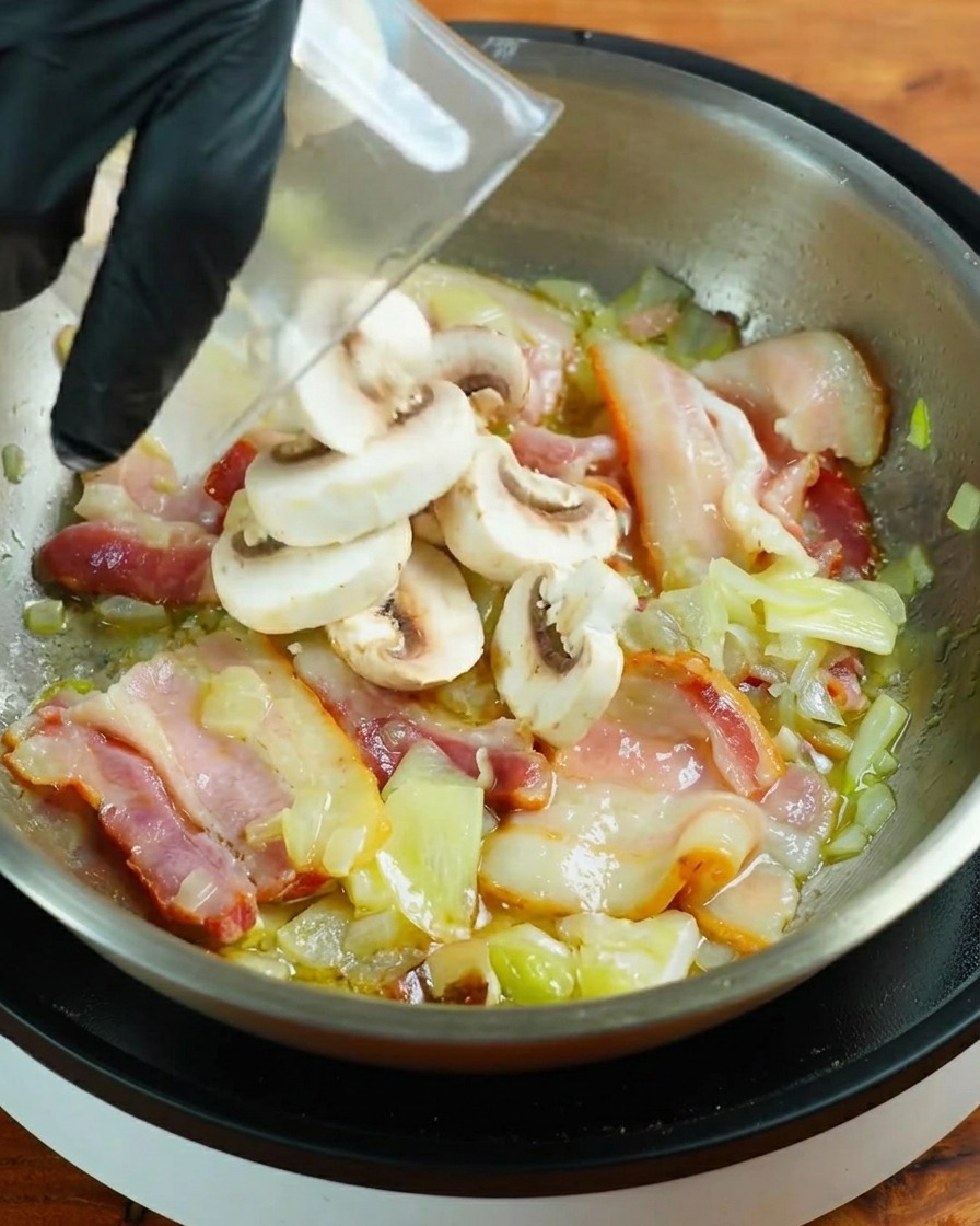 Champiñones blancos frescos laminados siendo añadidos a la sartén con el bacon.