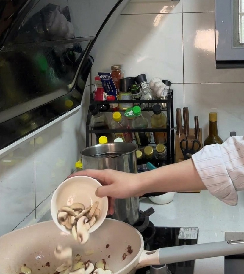 Cebolla picada y champiñones laminados cocinándose en la sartén con el tocino crujiente.