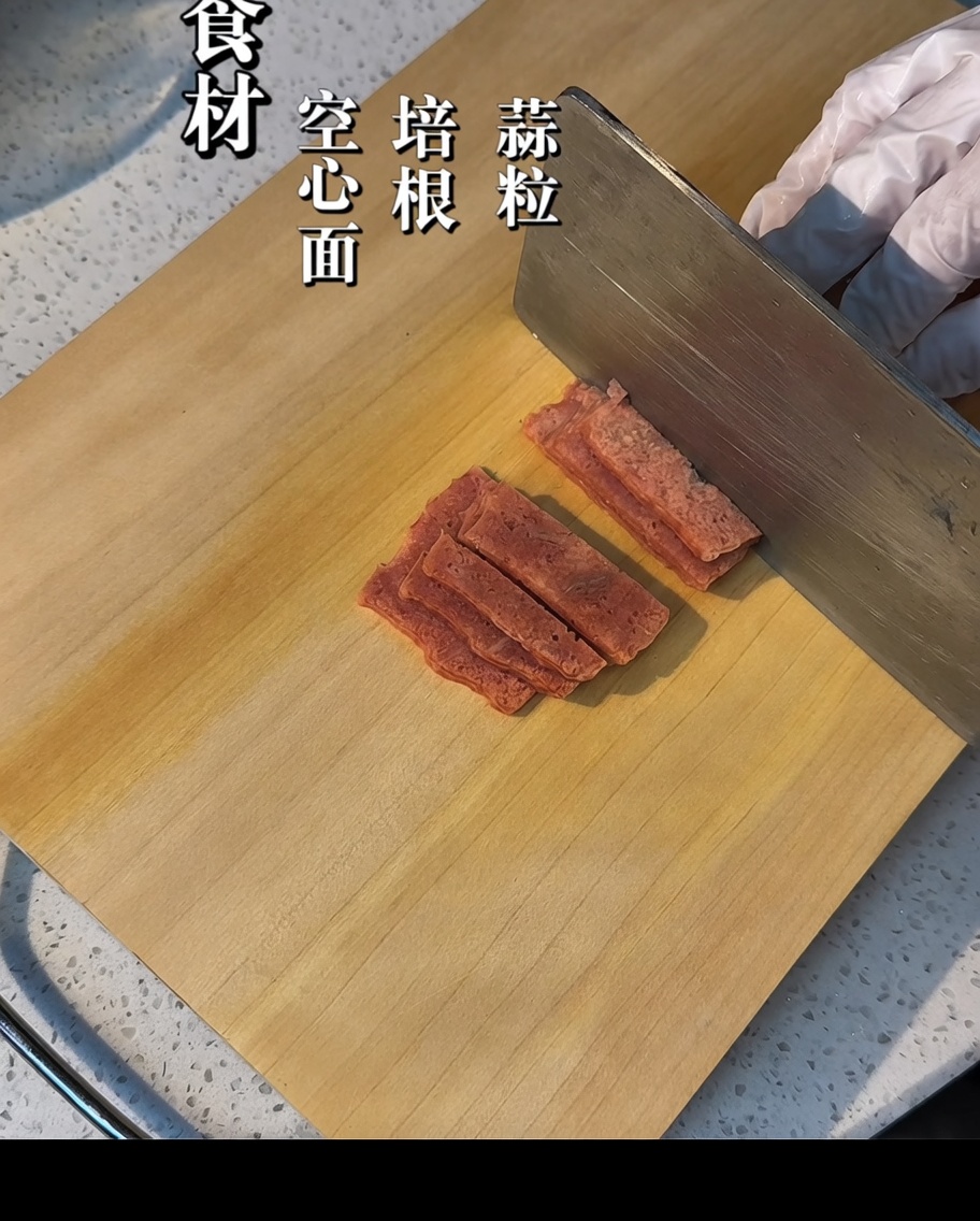 Tiras de tocino cortadas en trozos pequeños sobre una tabla de madera.